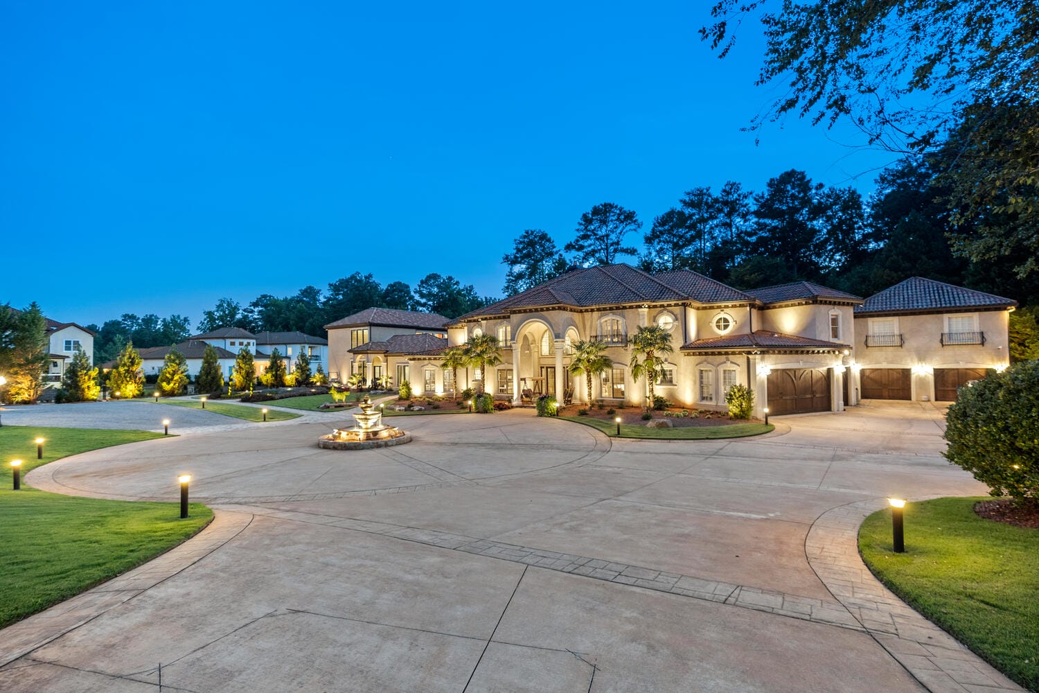Luxurious mansion exterior at twilight with landscaping lights