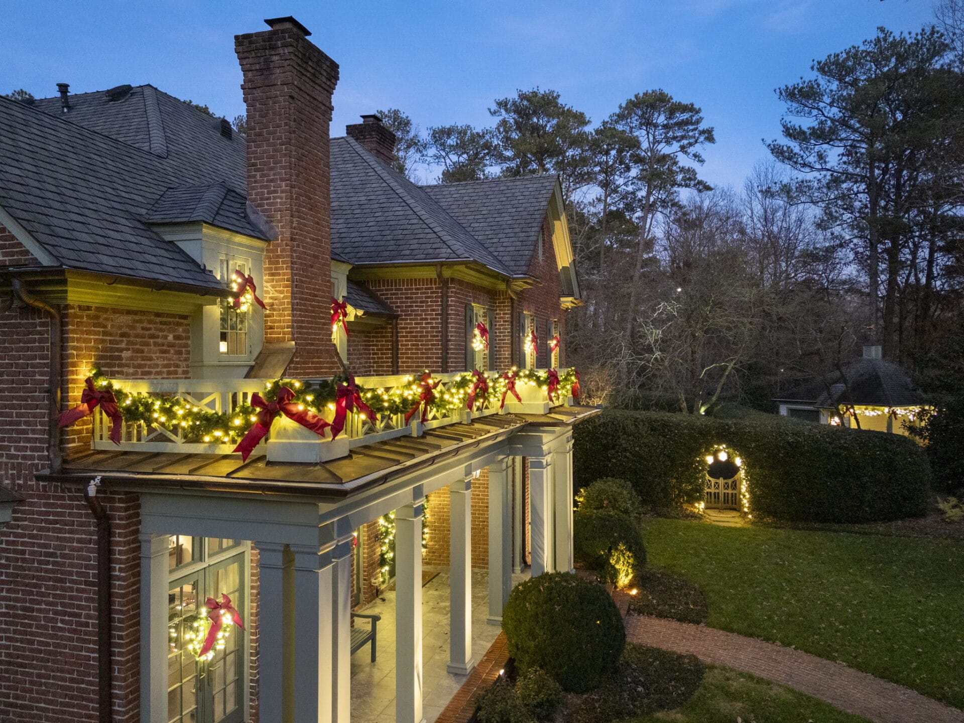 Brick house decorated with Christmas lights and wreaths.