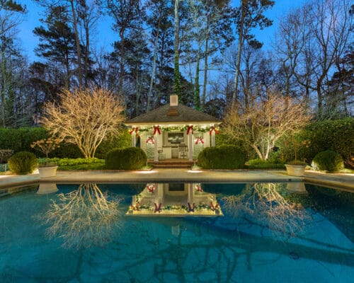 Festive poolside pavilion with holiday lights at twilight.