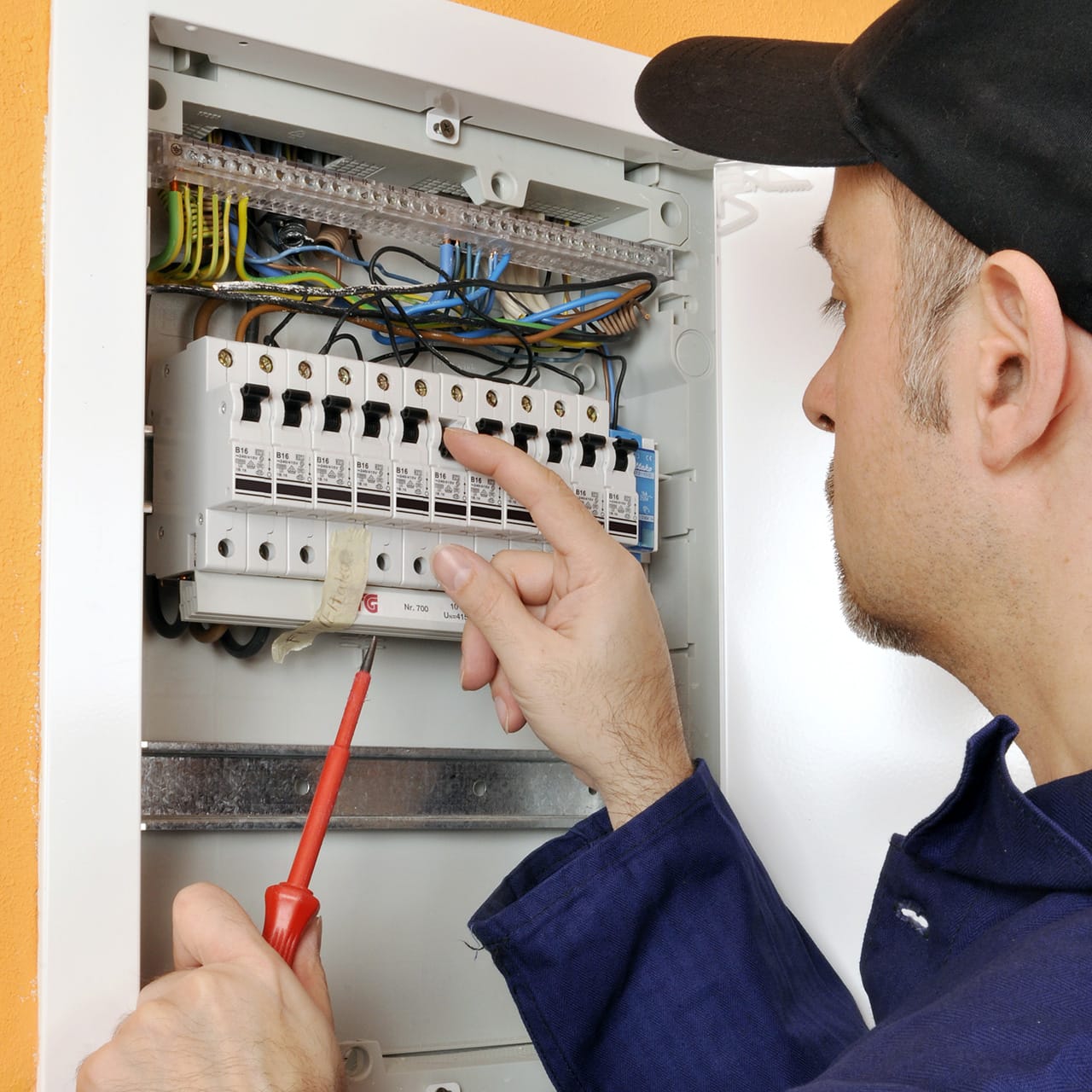 Electrician inspecting circuit breakers in panel box.