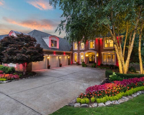 Luxury brick home with landscaped yard at dusk