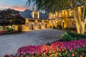 Luxury brick home with landscaped driveway at dusk