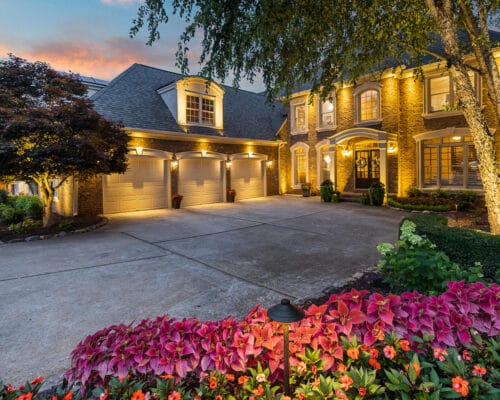 Luxury brick home with landscaped driveway at dusk