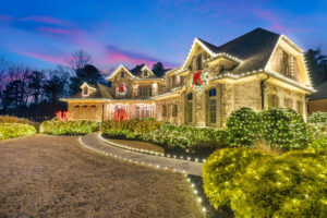 Large stone house decorated with Christmas lights at dusk